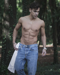 Shirtless man standing in forest