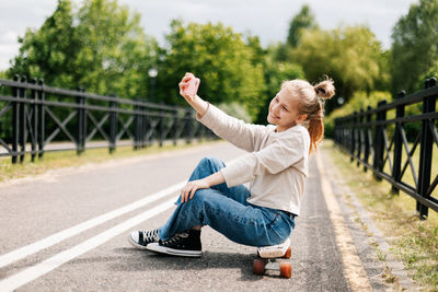 Cute blonde teenage girl sitting on a skateboard 