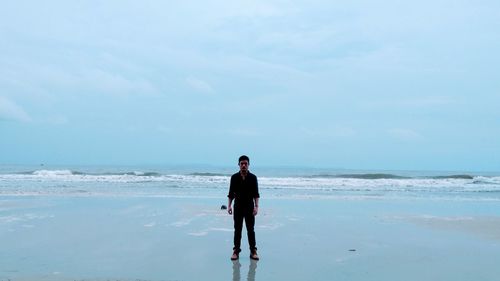 Full length of man standing on beach against sky
