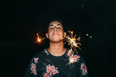 Portrait of woman with fire crackers at night