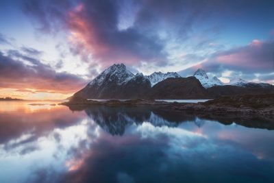 Scenic view of lake by mountains against sky during sunset