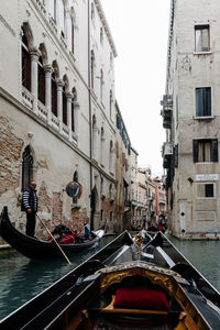 People in gondola on canal amidst buildings