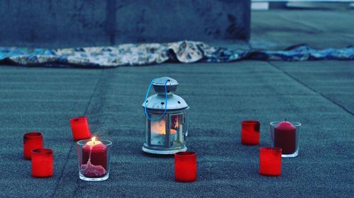 Illuminated red candle and lantern on footpath