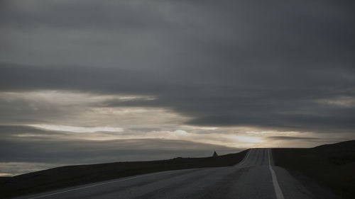 Country road against cloudy sky