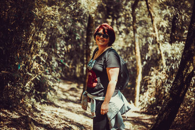 Portrait of smiling young woman standing in forest