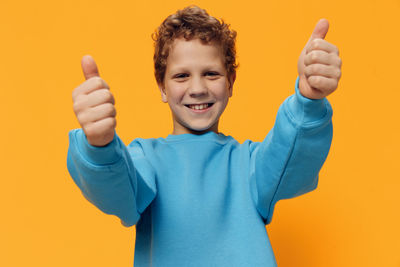 Portrait of boy gesturing against orange background