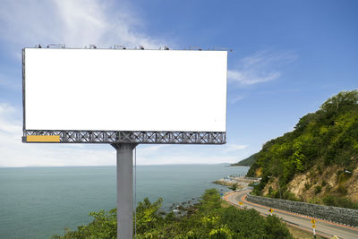 Information sign by road against sky