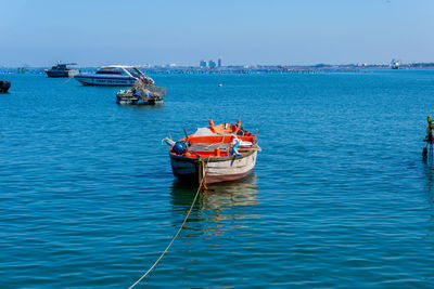 Boat sailing in sea against clear sky