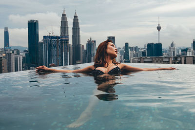 Full length of man and woman in swimming pool against sky