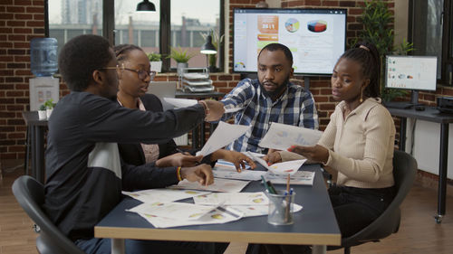 Colleagues discussing over documents at desk in office