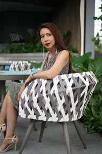 Portrait of woman sitting on chair at restaurant