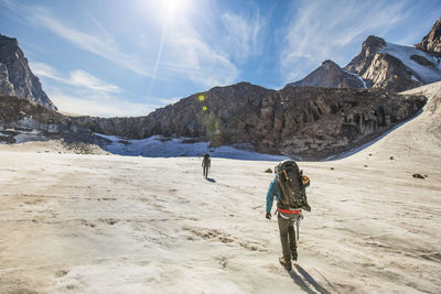 Mountaineers approach a headwall at the end of a glacier in mountains.