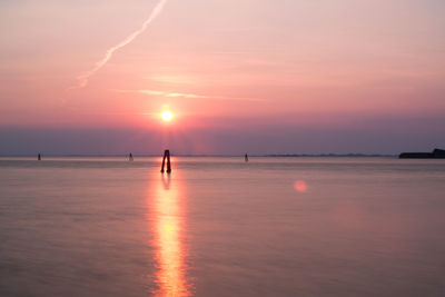 Silhouette man in sea against sky during sunset