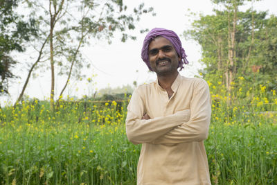 Portrait of young farmer standing at farm land