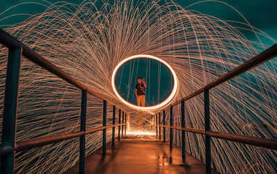Man spinning wire wool on footbridge