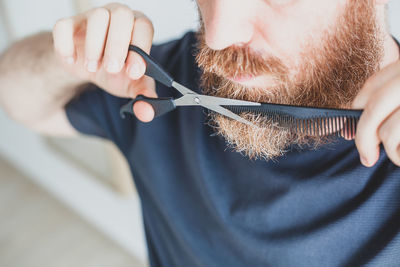 Close-up of man cutting beard