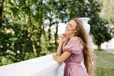 Portrait of young woman standing against trees