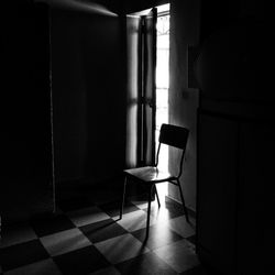 Empty chair on tiled floor in darkroom