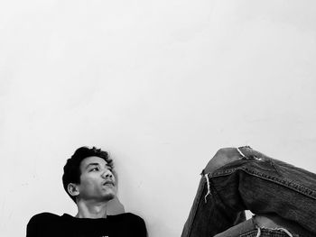 Portrait of young man looking away against white background