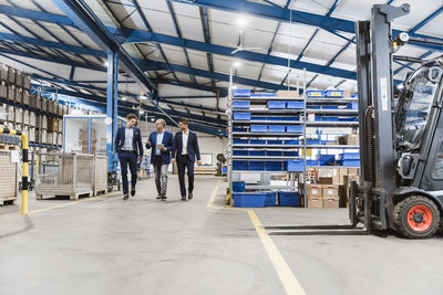 Three businessmen walking through shop floor, discussing decisions