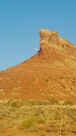 Low angle view of rocky mountain against clear blue sky