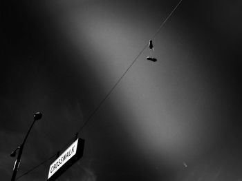 Low angle view of sign hanging against sky