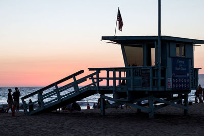 People at beach against sky during sunset