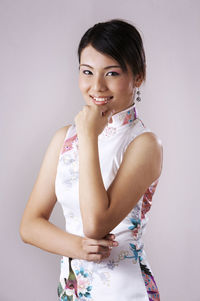 Portrait of happy young woman standing against gray background