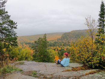 Man sitting on plant against trees during autumn