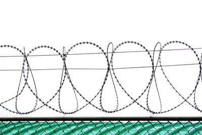 Close-up of barbed wire fence against sky