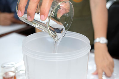 Midsection of woman pouring drink in glass