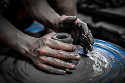 Midsection of man working on pottery wheel