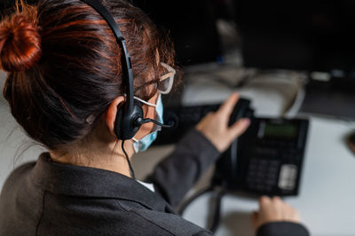 Rear view of woman using landline