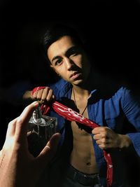 Portrait of young man making face against black background