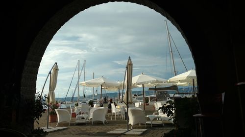 Chairs and table by sea against sky