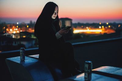 Woman standing by railing at night