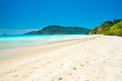 Panorama of beautiful beach at tropical island with white sand and green trees