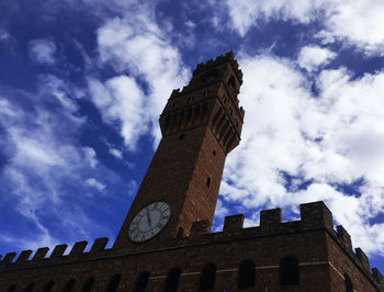 Low angle view of clock tower against cloudy sky