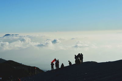 Silhouette people on landscape against blue sky