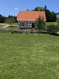 Lawn by house on field against clear sky