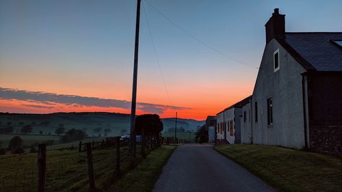 Street amidst buildings against sky during sunset