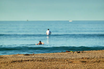 Rear view of surfing man on beach against sky