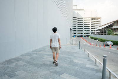 Full length rear view of man walking on modern building