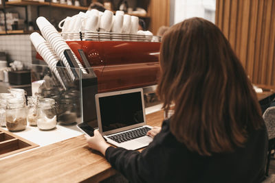 Adult confident business woman freelancer working in a coffee shop cafe using a laptop and phone