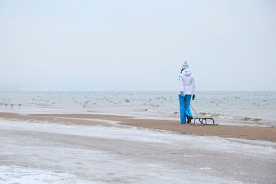 Rear view of person standing on beach against clear sky