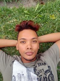 Portrait of young man lying on field