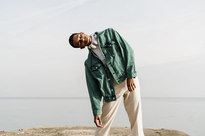 Side view of young man standing at beach