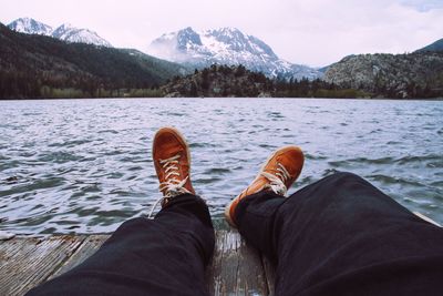 Low section of man standing by lake against sky