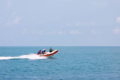 People on motorboat in sea against sky