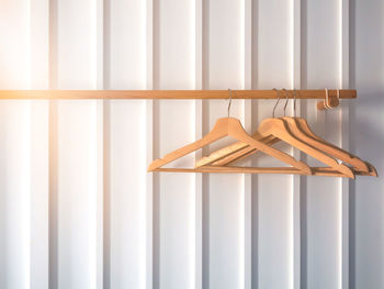 Wooden hangers for hanging clothes with wood clothes rack on white stripe wall.